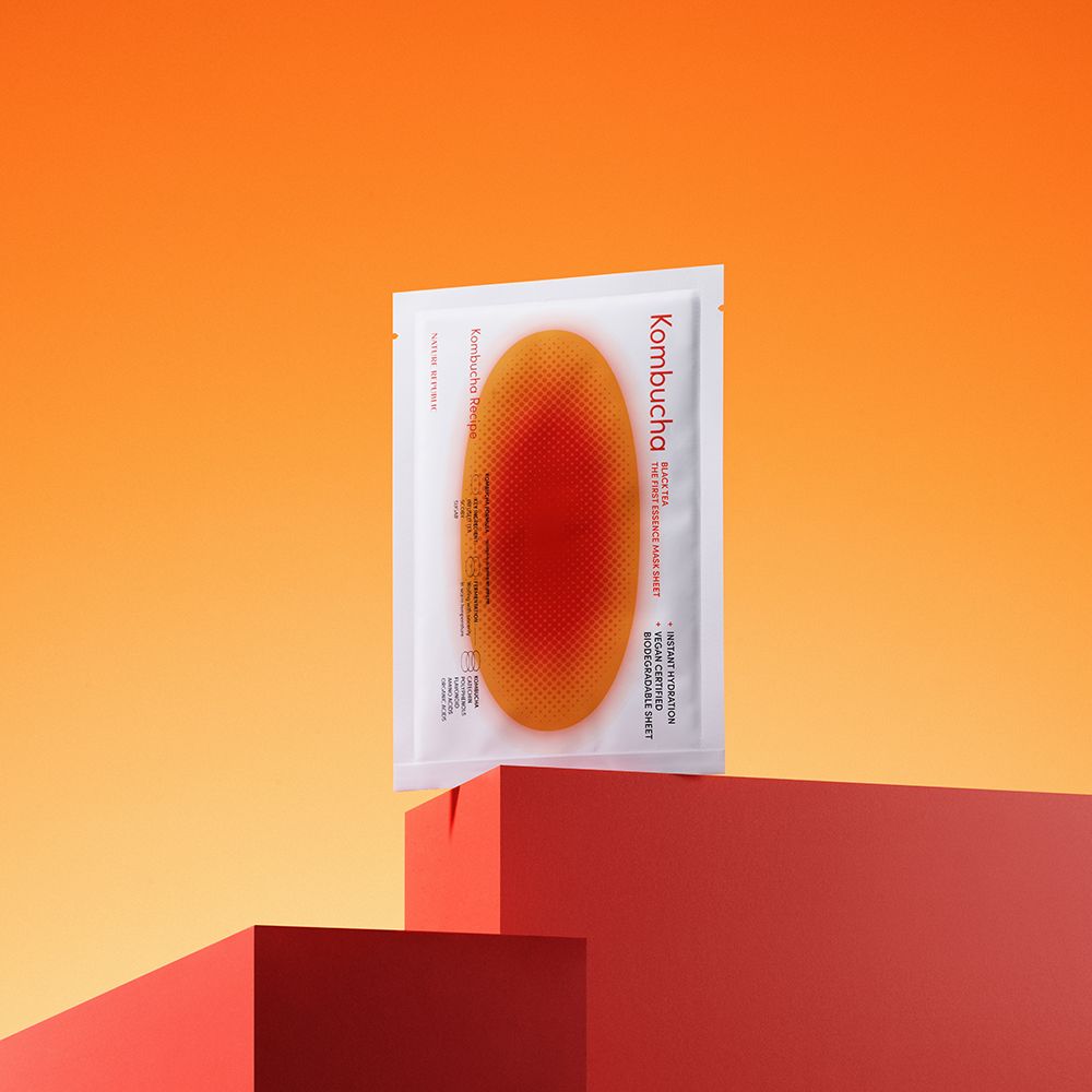 Emballage produit sur surface rouge. Masque orange visible. Texte: Kombucha, Black Tea, Instant Hydration, Vegan Certified, Biodegradable Sheet.