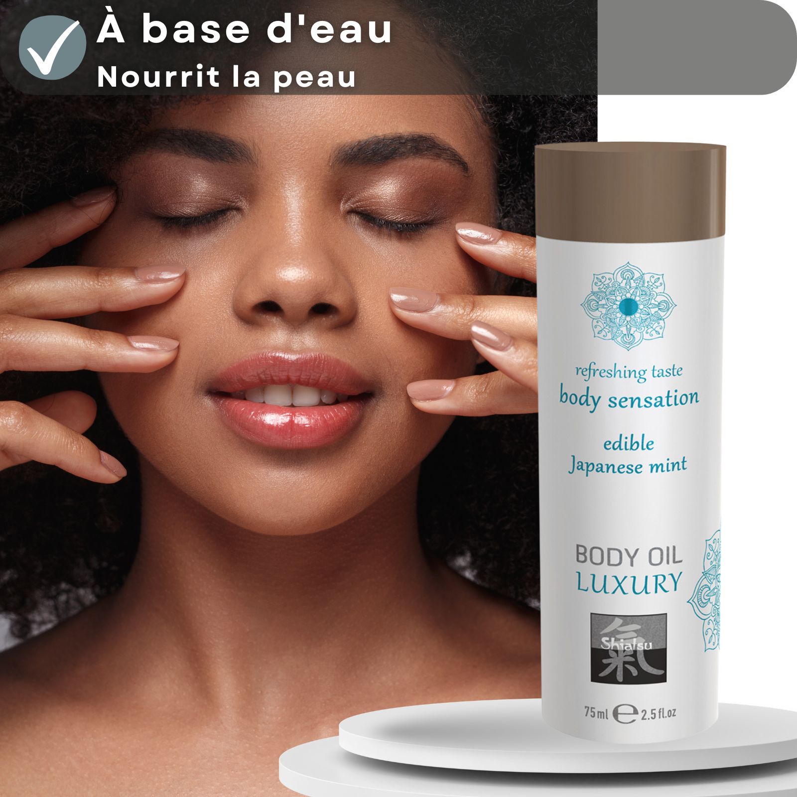 Flacon d'huile corporelle Shiatsu Luxury devant des feuilles de menthe. Base aqueuse, nourrit la peau.