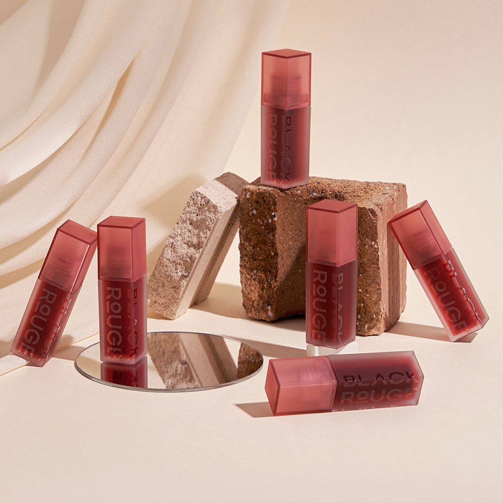 Plusieurs flacons de gloss disposés sur une surface. Les flacons portent l'inscription BLACK ROUGE.