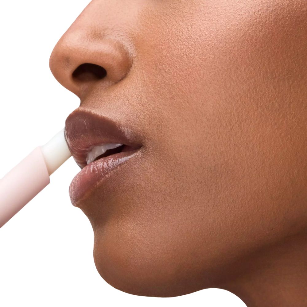 Lippen van een persoon die een lipgloss-stick gebruikt. De stick is roze.