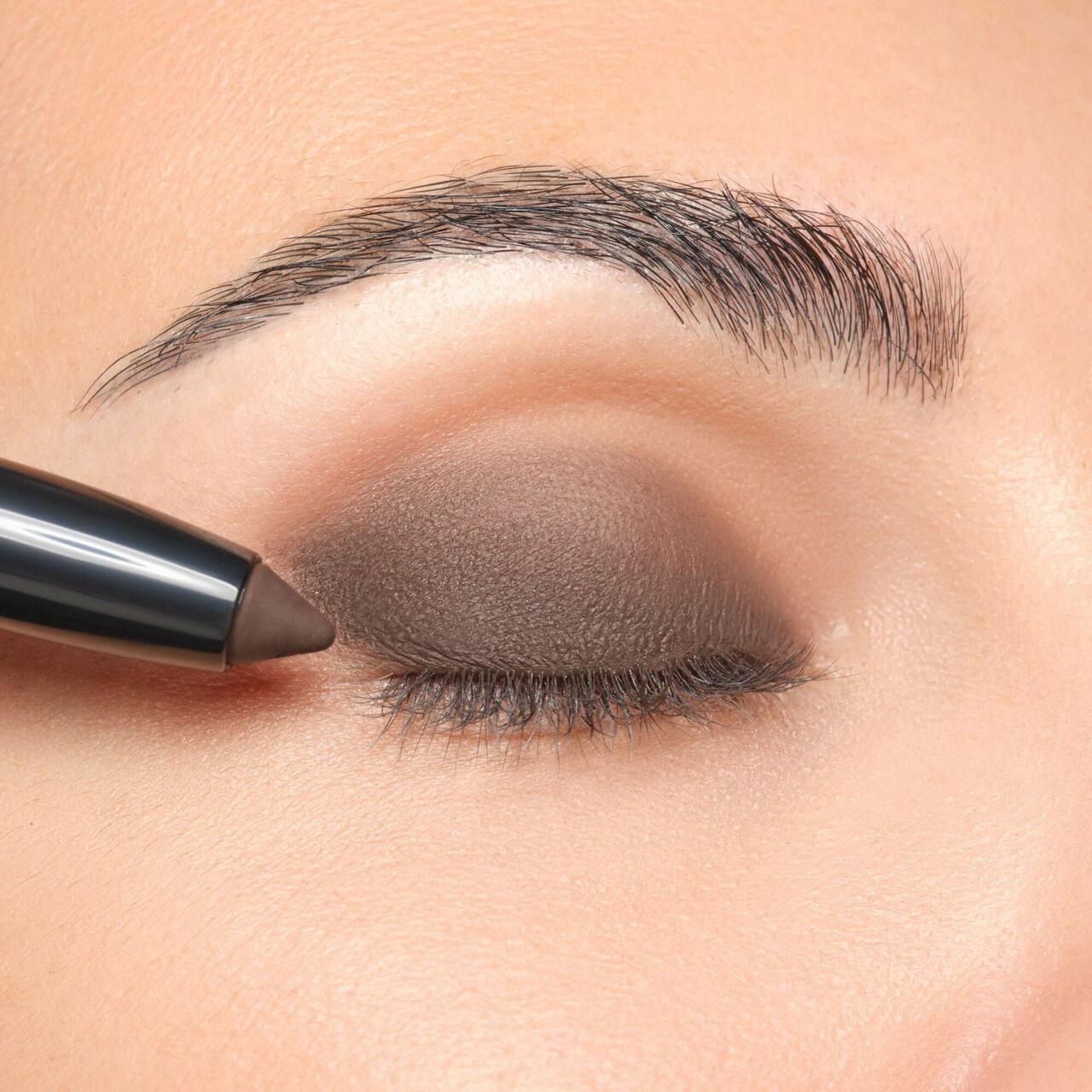 Oog met bruine oogschaduw. Een Eyeshadow Stylo wordt aangebracht.