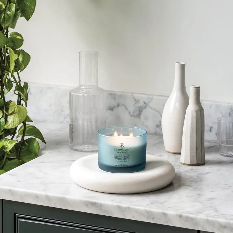 Bougie bleue Chesapeake Bay, mind & body, reflection + clarity, sur socle blanc. Décoration avec vases.