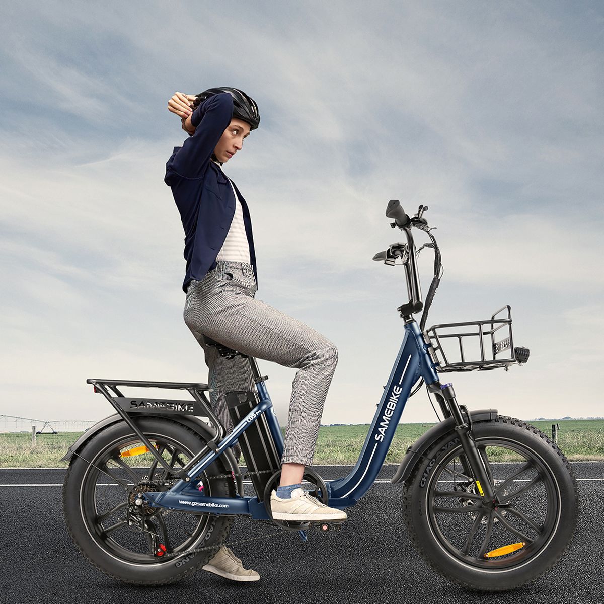 Persoon zit op blauwe SAMEBIKE C05 Pro e-bike. Helm, weg op achtergrond. Merk SAMEBIKE zichtbaar.