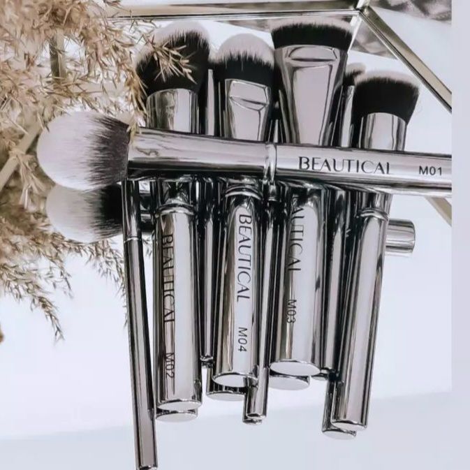 Set de pinceaux avec manches argentés. La marque BEAUTICAL est visible. Sur un miroir.