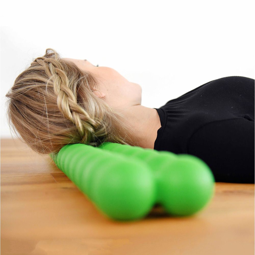 Een vrouw ligt met haar hoofd op een groene Spinefitter. De achtergrond is licht en houten.