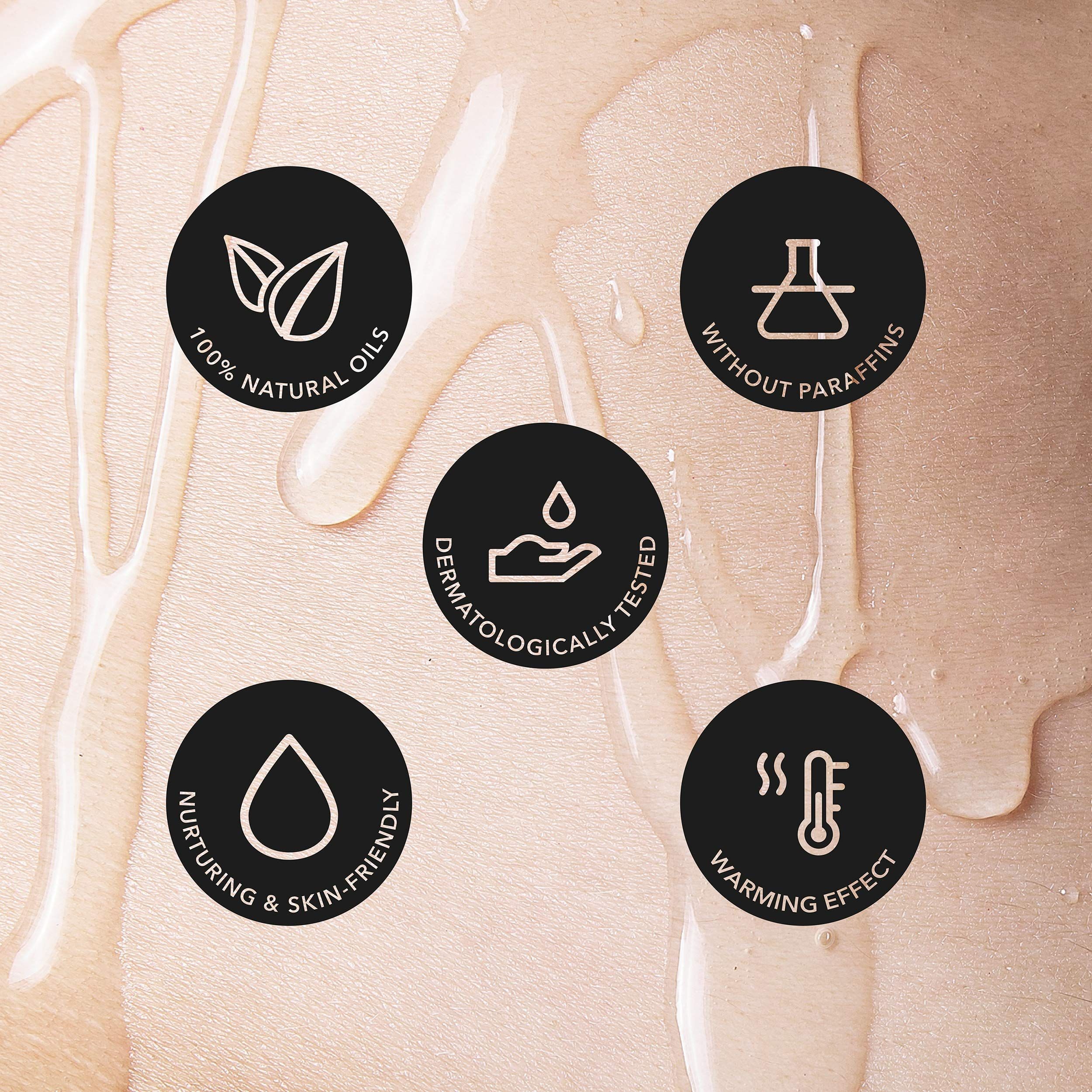 Fles Loovara Warm Up massageolie met geel etiket, omringd door oliespetters.