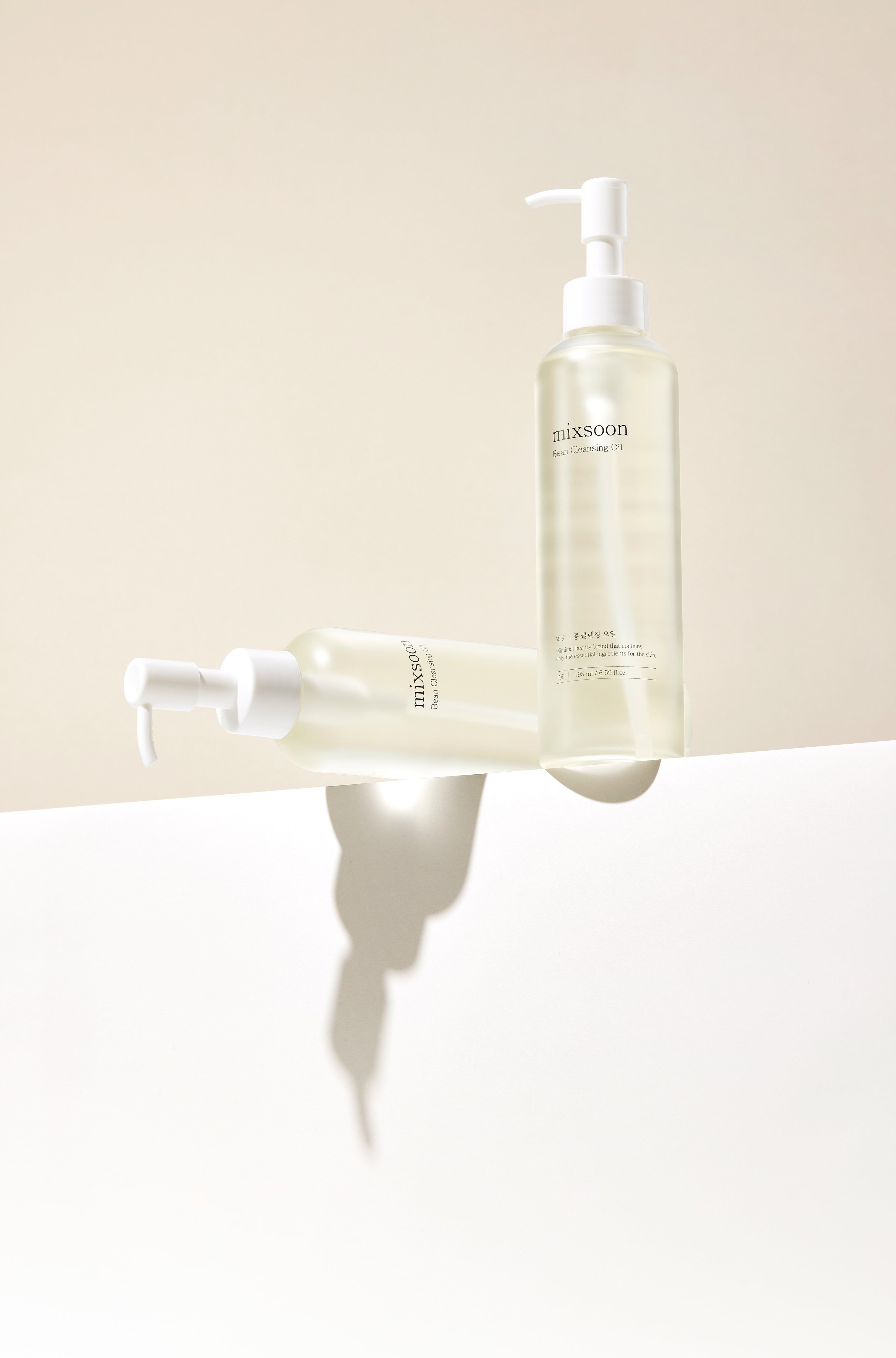 Twee flessen mixsoon Bean Cleansing Oil op een wit oppervlak met schaduw.
