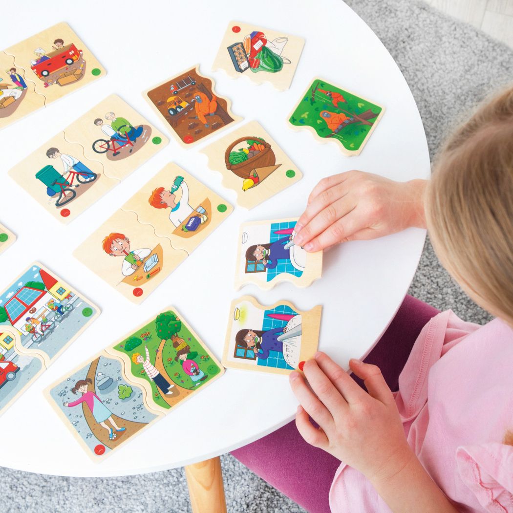 Enfant jouant avec des puzzles sur une table blanche. Différentes pièces de puzzle avec illustrations. L'enfant touche une pièce.