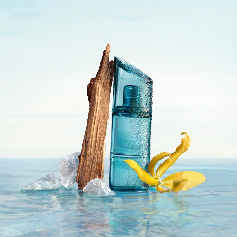 Flacon bleu Kenzo Homme Eau de Toilette Marine avec bois, glace et fleur jaune dans l'eau.