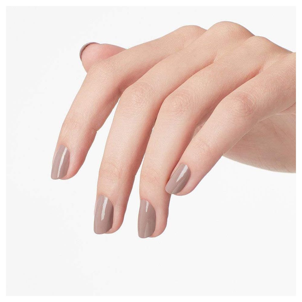 Main avec ongles vernis taupe. Les ongles sont recouverts de vernis.