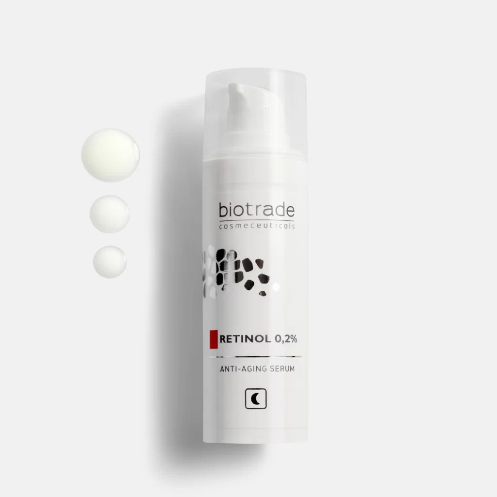 Sérum blanc avec pompe et bouchon transparent. Inscription: Biotrade, Retinol 0,2%, Anti-Aging Serum. Trois gouttes de sérum.