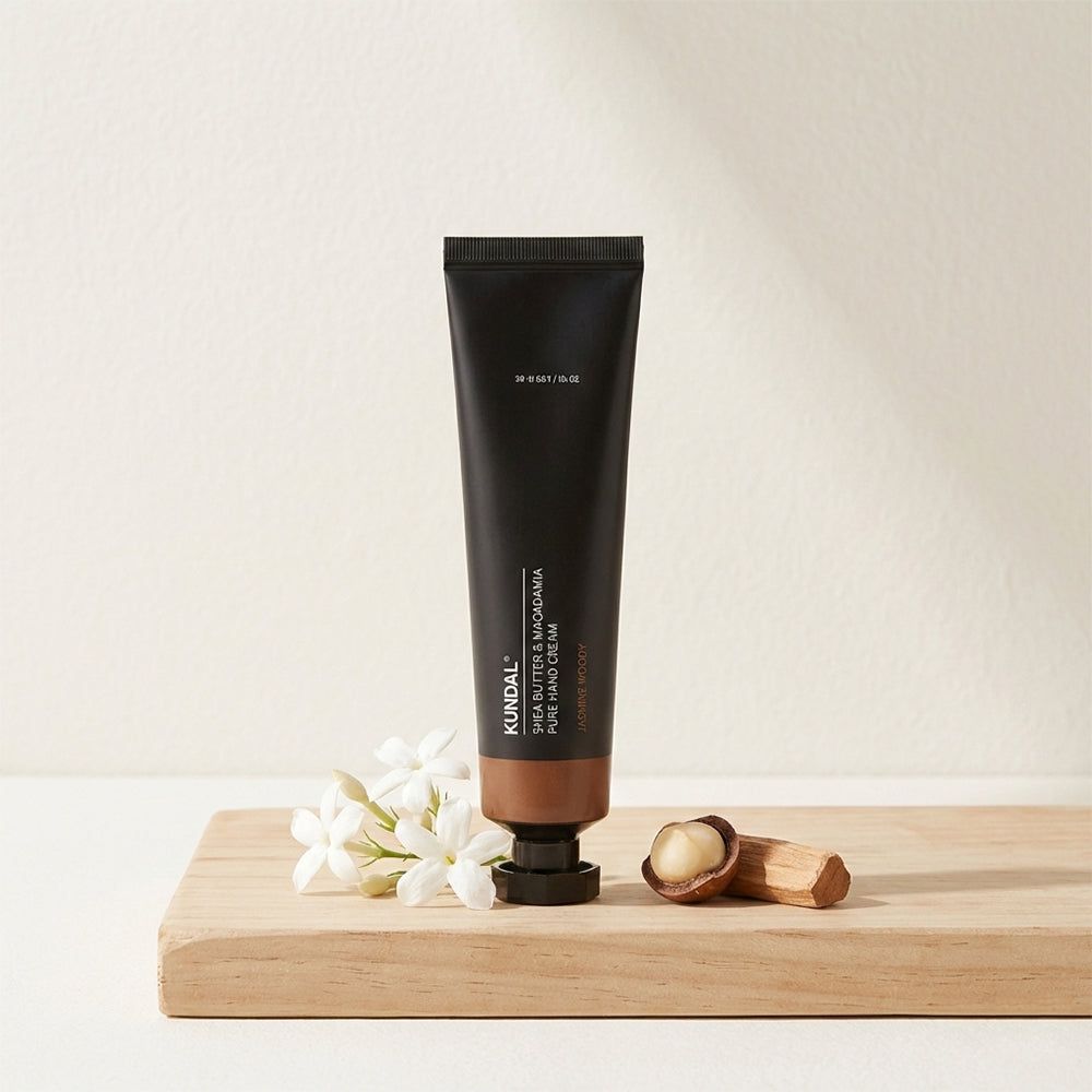 KUNDAL handcrème tube met macadamianoten en bloemen op een houten plank.