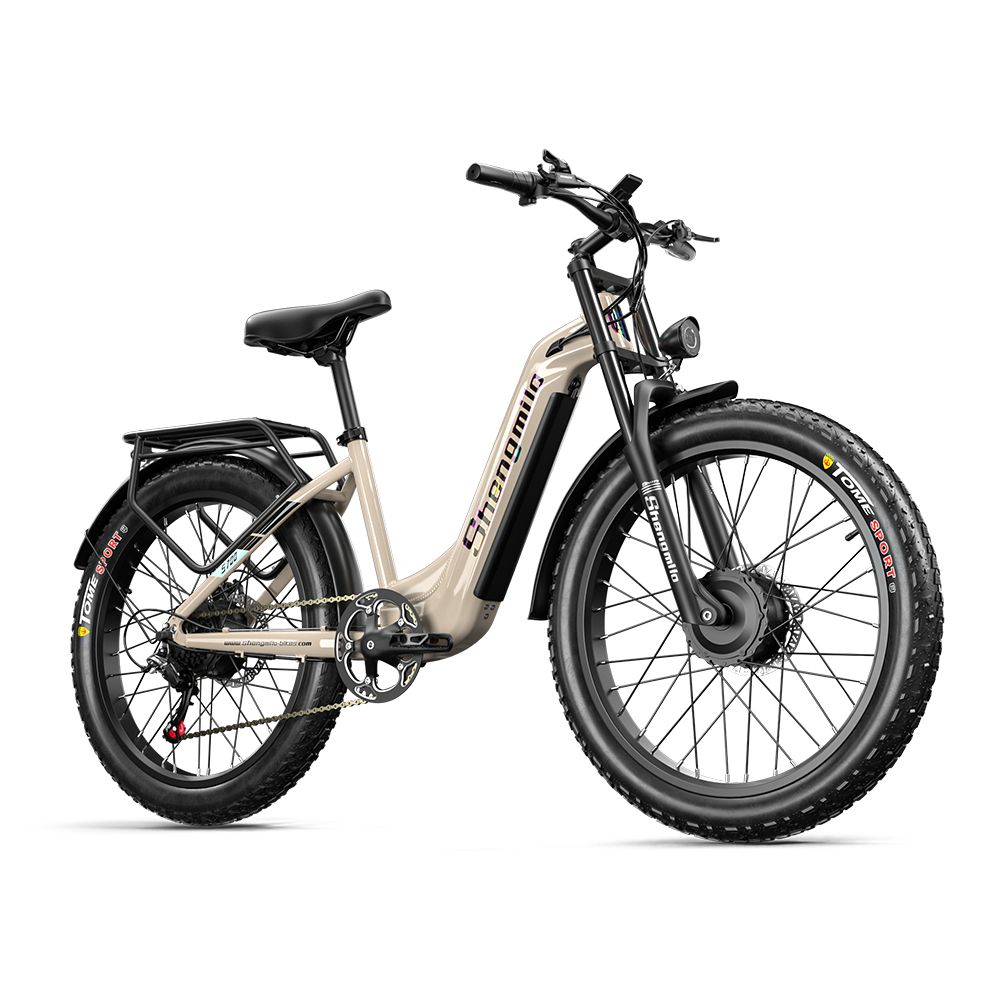 E-bike, vue diagonale. Cadre beige, pneus noirs. Marque Shengmilo visible. Porte-bagages et garde-boue.