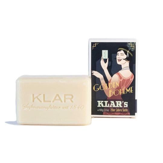 Savon à côté de l'emballage. Savon avec l'inscription KLAR'S. Emballage rétro. Inscription: GOLDEN BOHEME, KLAR'S, 20er Jahre Seife.