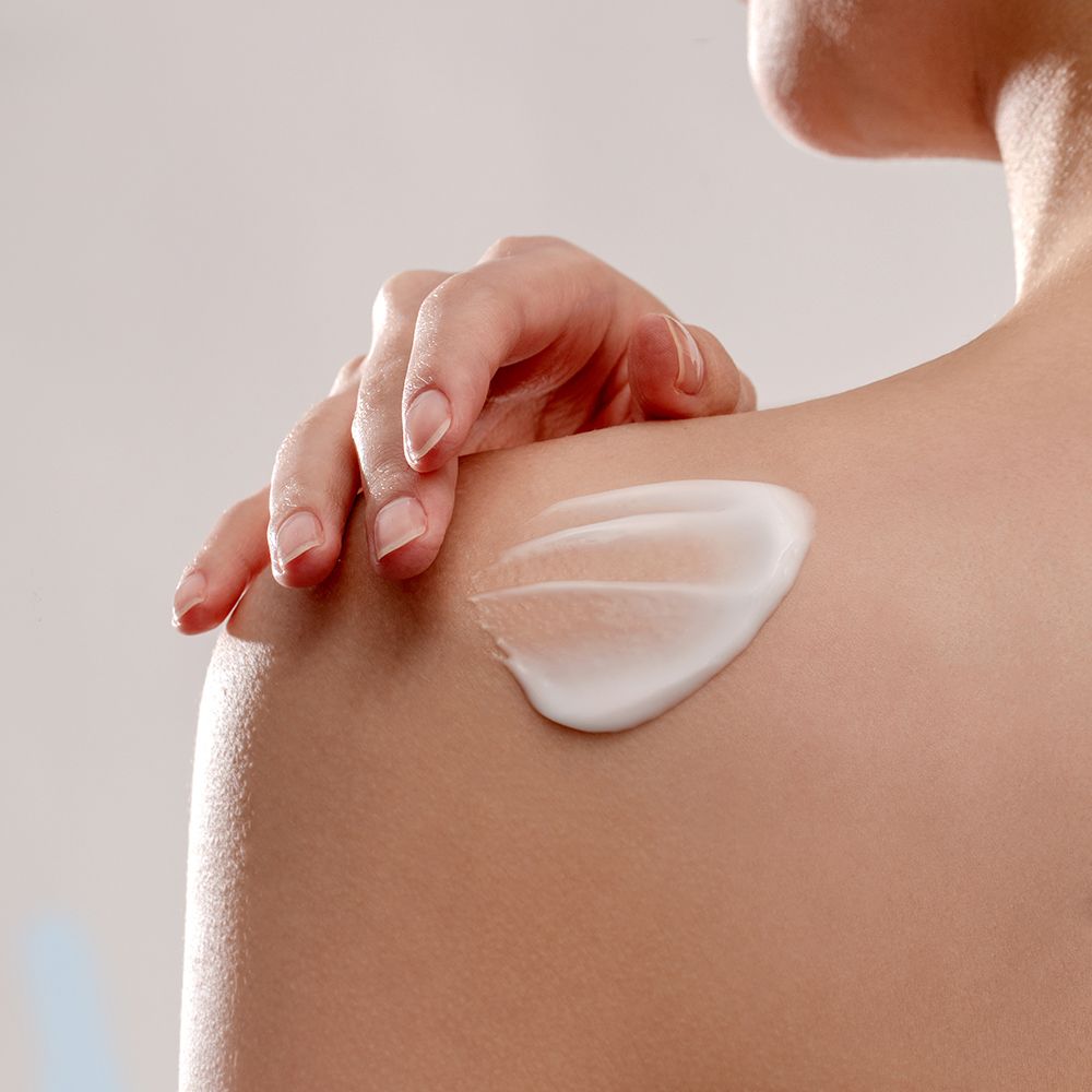 Wit product aangebracht op schouder. Huidskleur zichtbaar.