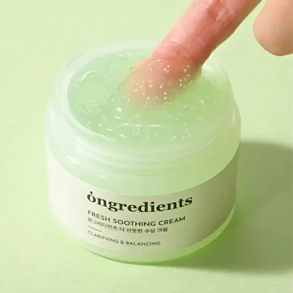 Pot de crème ouvert avec crème verte. Un doigt touche la crème. Inscription : ONGREDIENTS, FRESH SOOTHING CREAM, texte coréen, CLARIFYING & BALANCING.