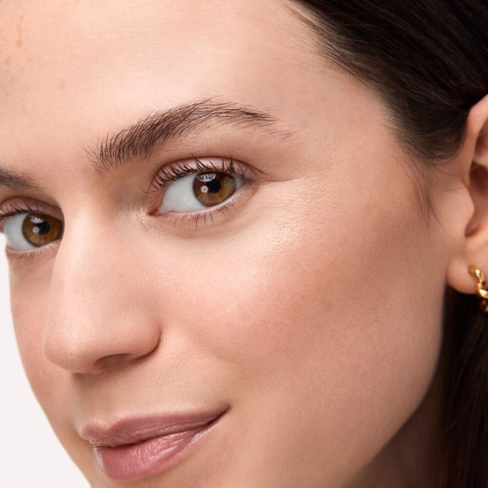 Gros plan d'un visage avec surligneur appliqué. Teint et couleur des yeux visibles.