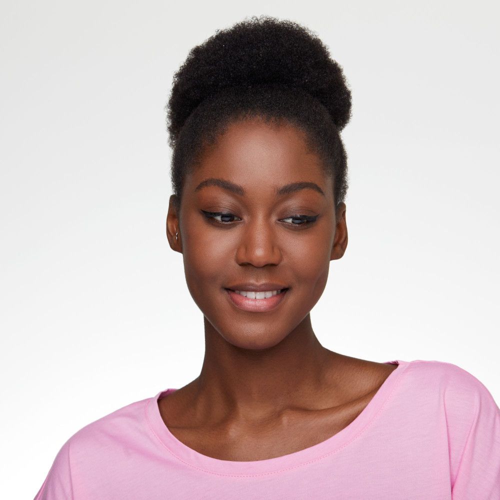 Portrait d'une femme maquillée. Elle porte un pull rose. Le regard est dirigé vers le bas.