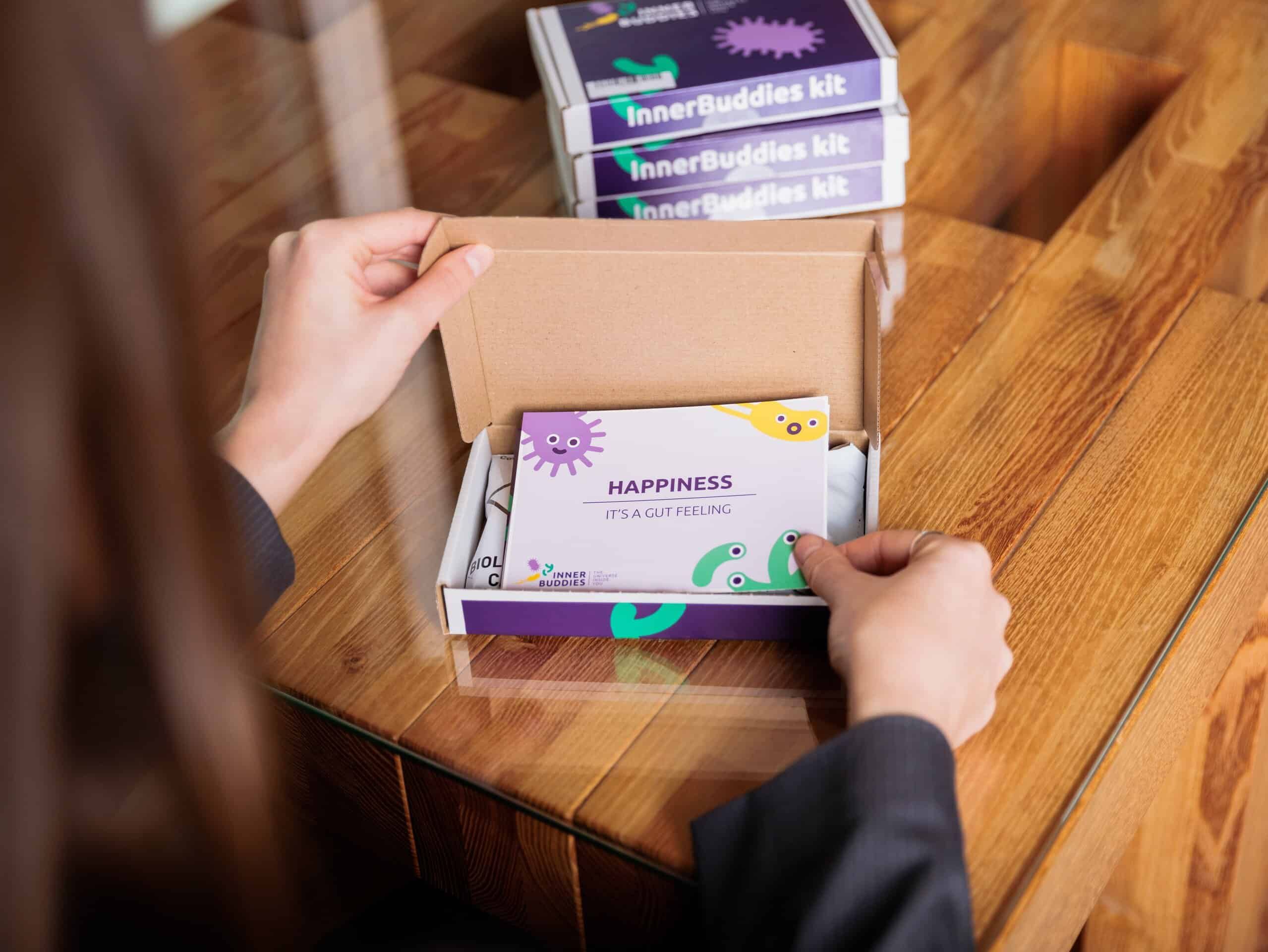 Persoon opent een Inner Buddies testkit verpakking en onthult de inhoud.
