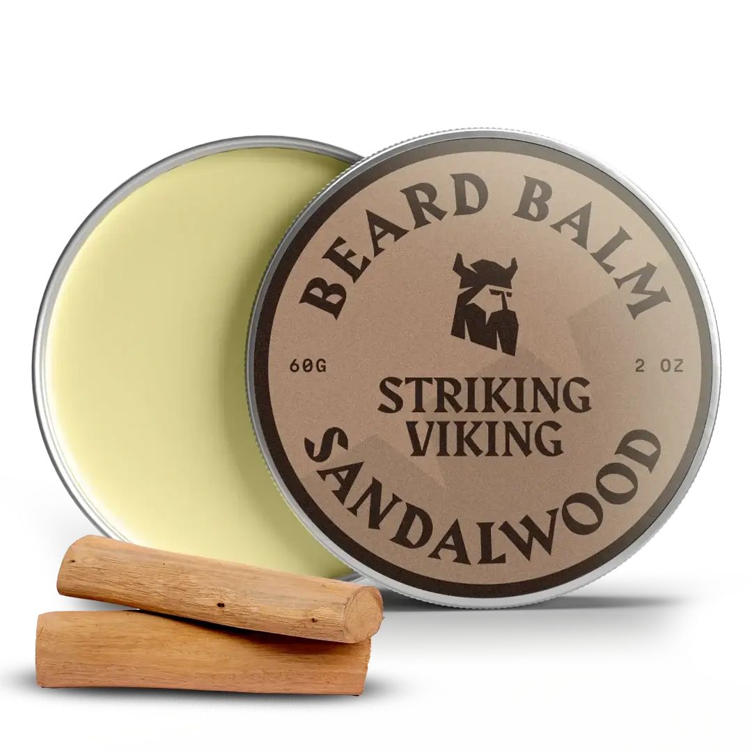 Boîte de baume à barbe ouverte. Couvercle avec inscription: BEARD BALM, STRIKING VIKING, SANDALWOOD. Deux morceaux de bois à côté.