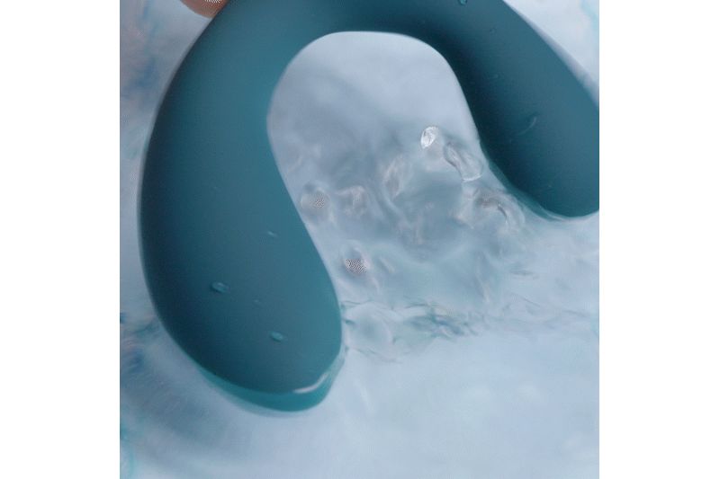 Blauwgroene vibrator in water. U-vormig, afgeronde uiteinden. Water omringt het product.