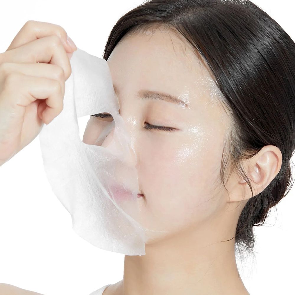 Gezichtsmasker wordt aangebracht. Wit masker, vrouw houdt masker vast. Huidverzorgingsproduct.