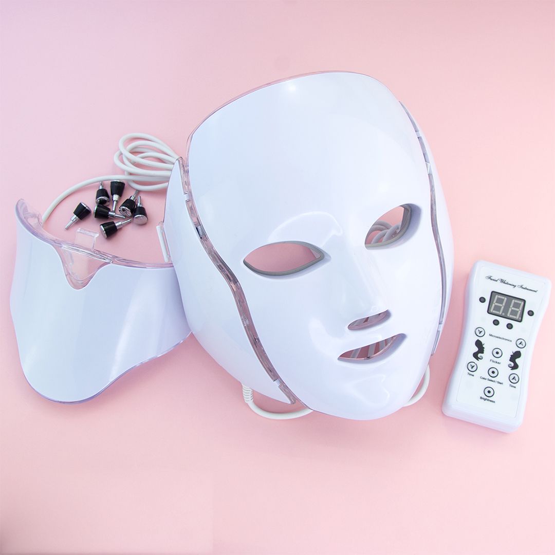 Wit LED-gezichtsmasker met nekstuk, afstandsbediening en accessoires. Het masker heeft openingen voor ogen, neus en mond.