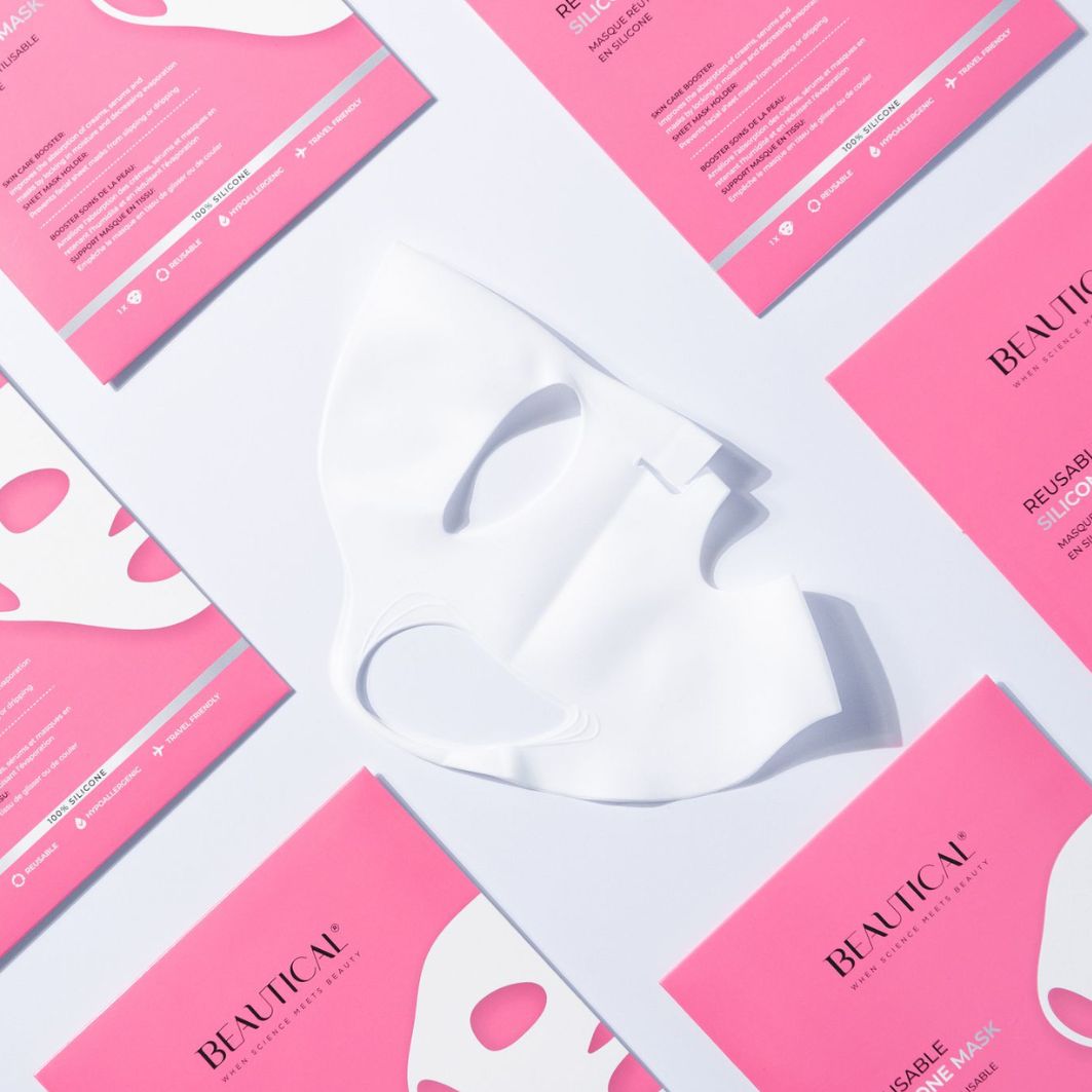 Wit siliconen masker en roze verpakkingen. Tekst: BEAUTICAL, REUSABLE SILICONE MASK. Masker ligt op verpakkingen.