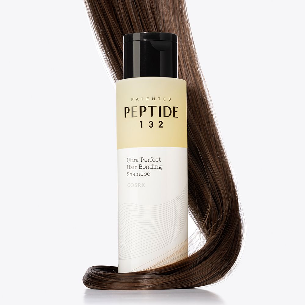Bouteille de shampoing PEPTIDE-132 Ultra Perfect Hair Bonding enroulée dans des cheveux foncés.