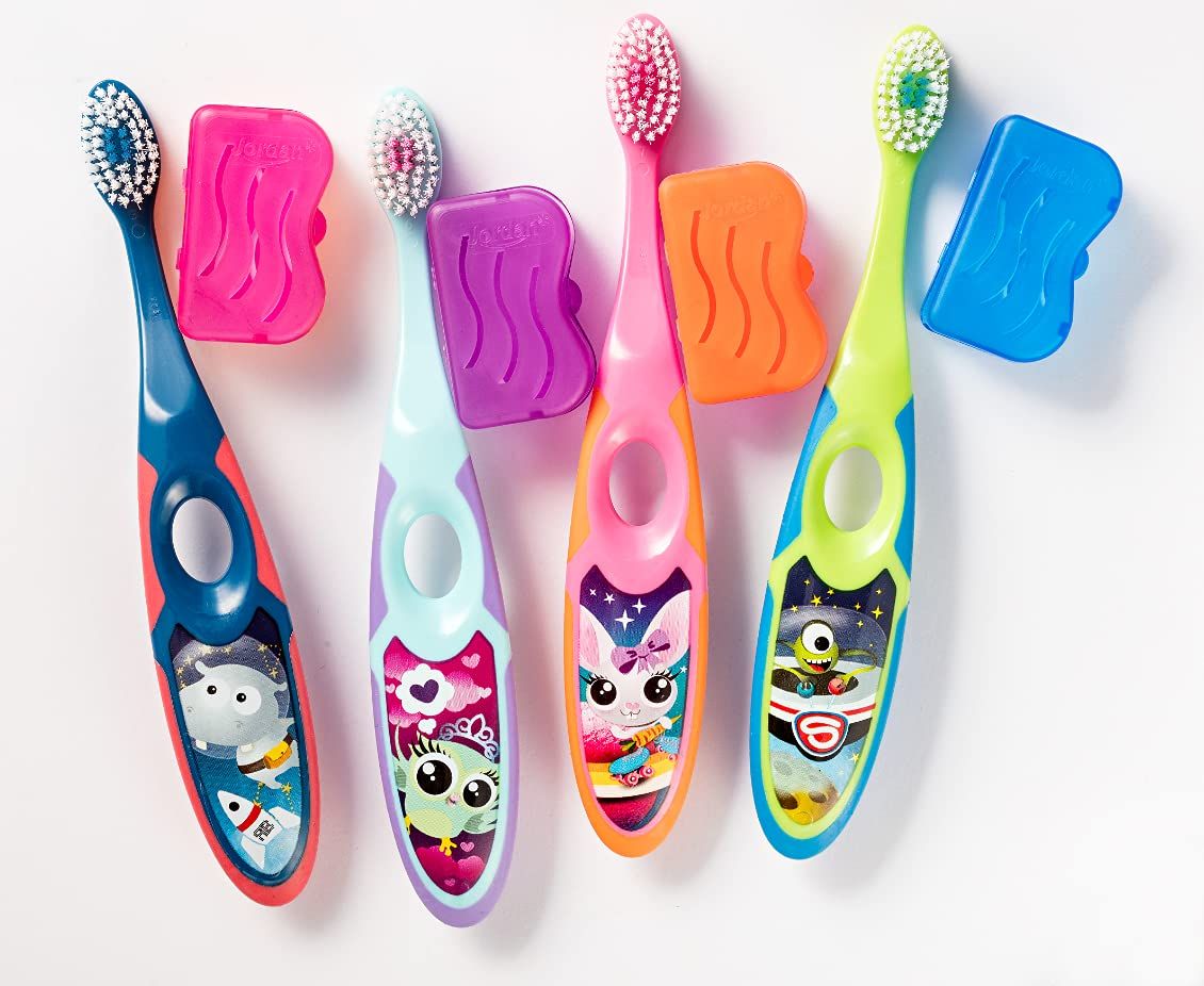 Quatre brosses à dents pour enfants avec motifs d'animaux et capuchons protecteurs.