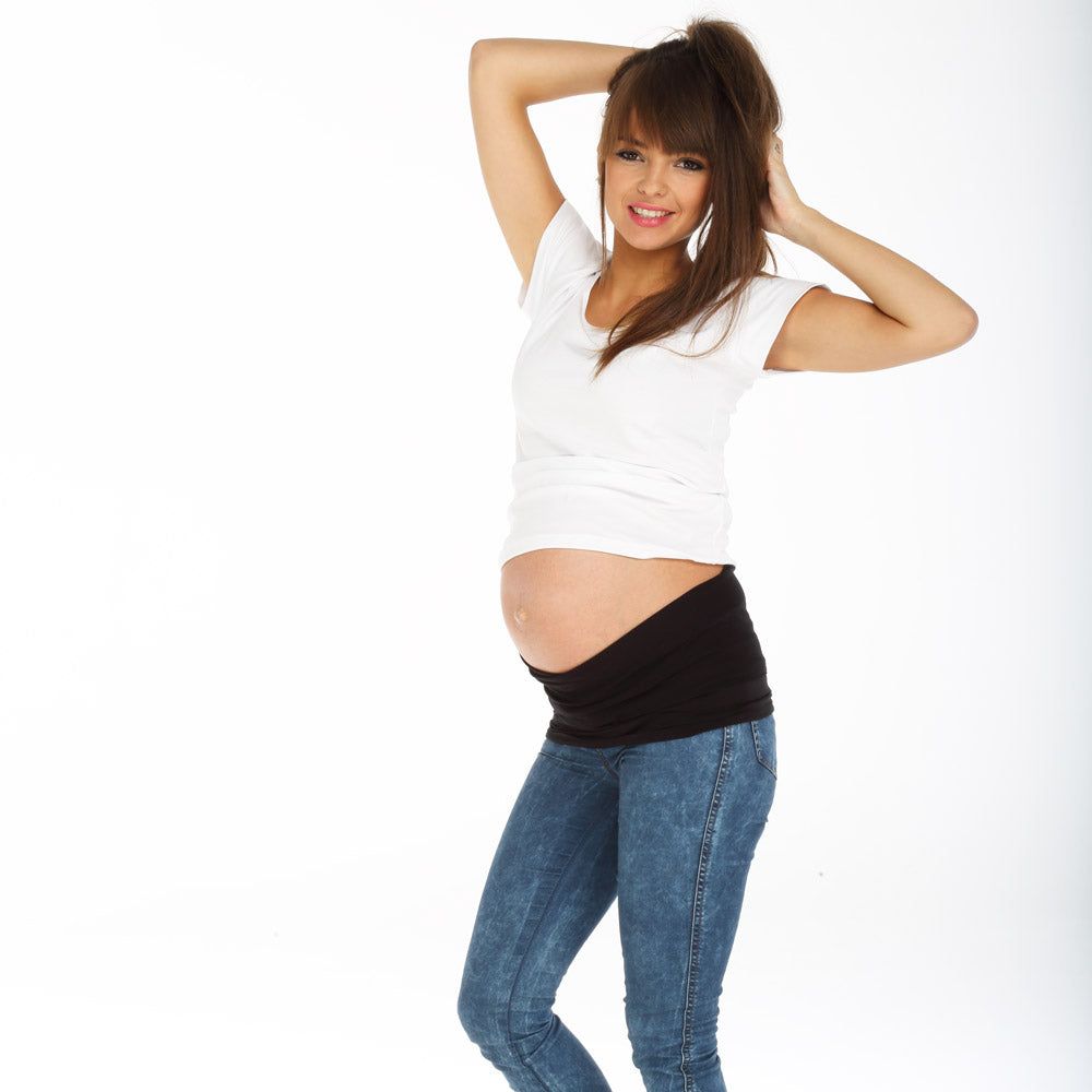 Bande de grossesse noire portée par une femme en jean et t-shirt blanc. La bande couvre le ventre.