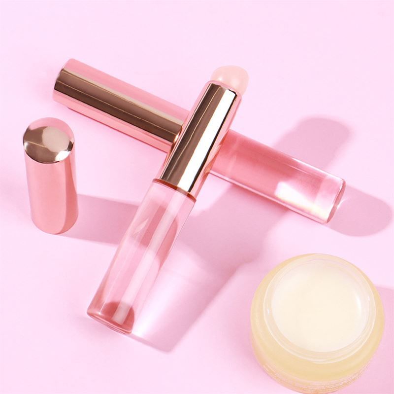 Deux pinceaux, un capuchon et un pot sur fond rose. Pinceaux avec manche rose et applicateur clair.