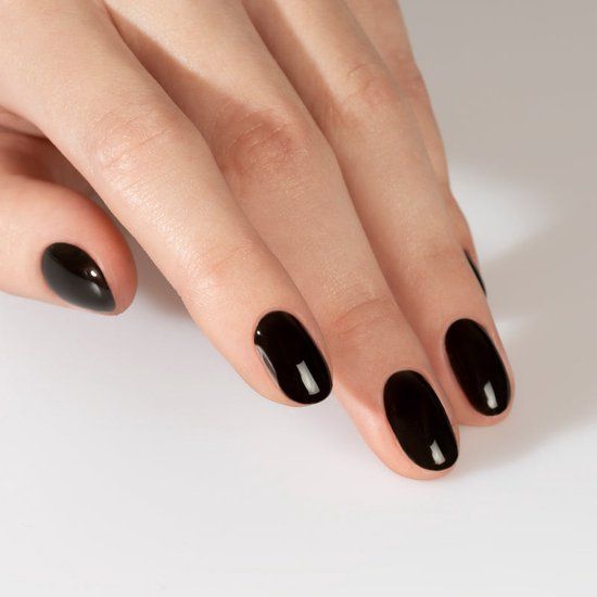 Main avec ongles vernis. Ongles vernis de vernis noir. Finition brillante.