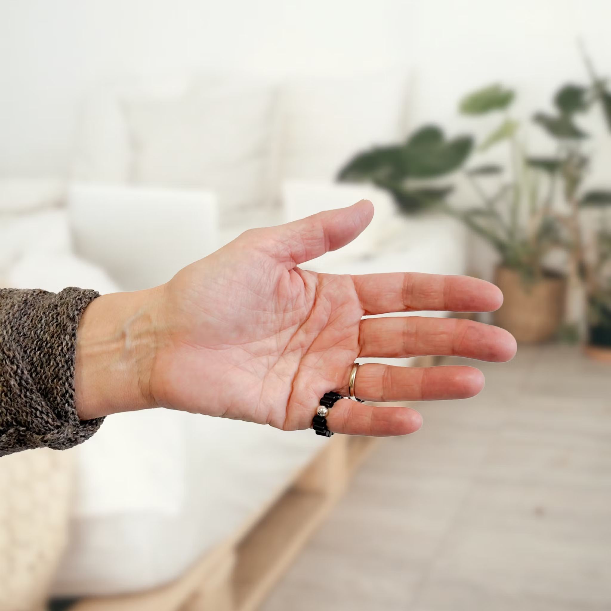Main avec bague noire et bille argentée. Produit de bien-être.