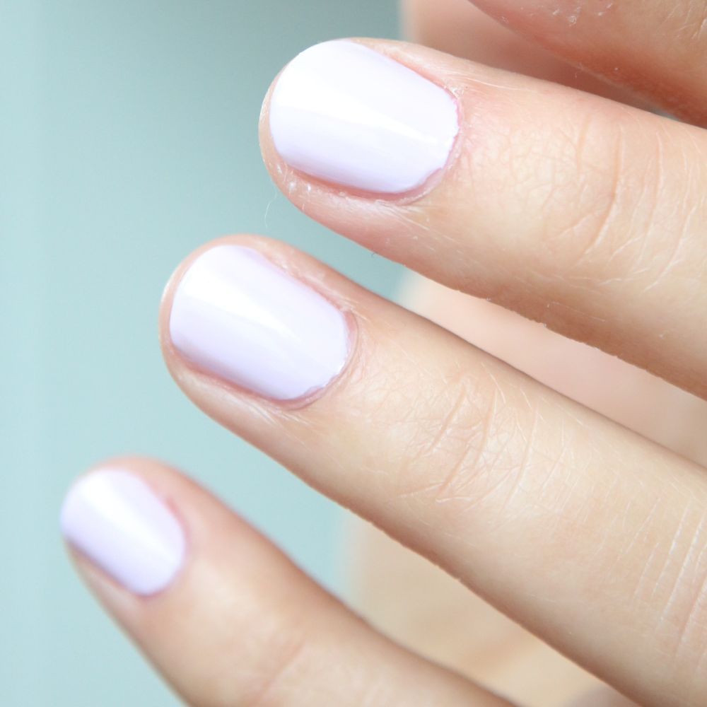 Close-up van vingers met lichtpaarse nagellak. De nagels zijn kort en gelakt.