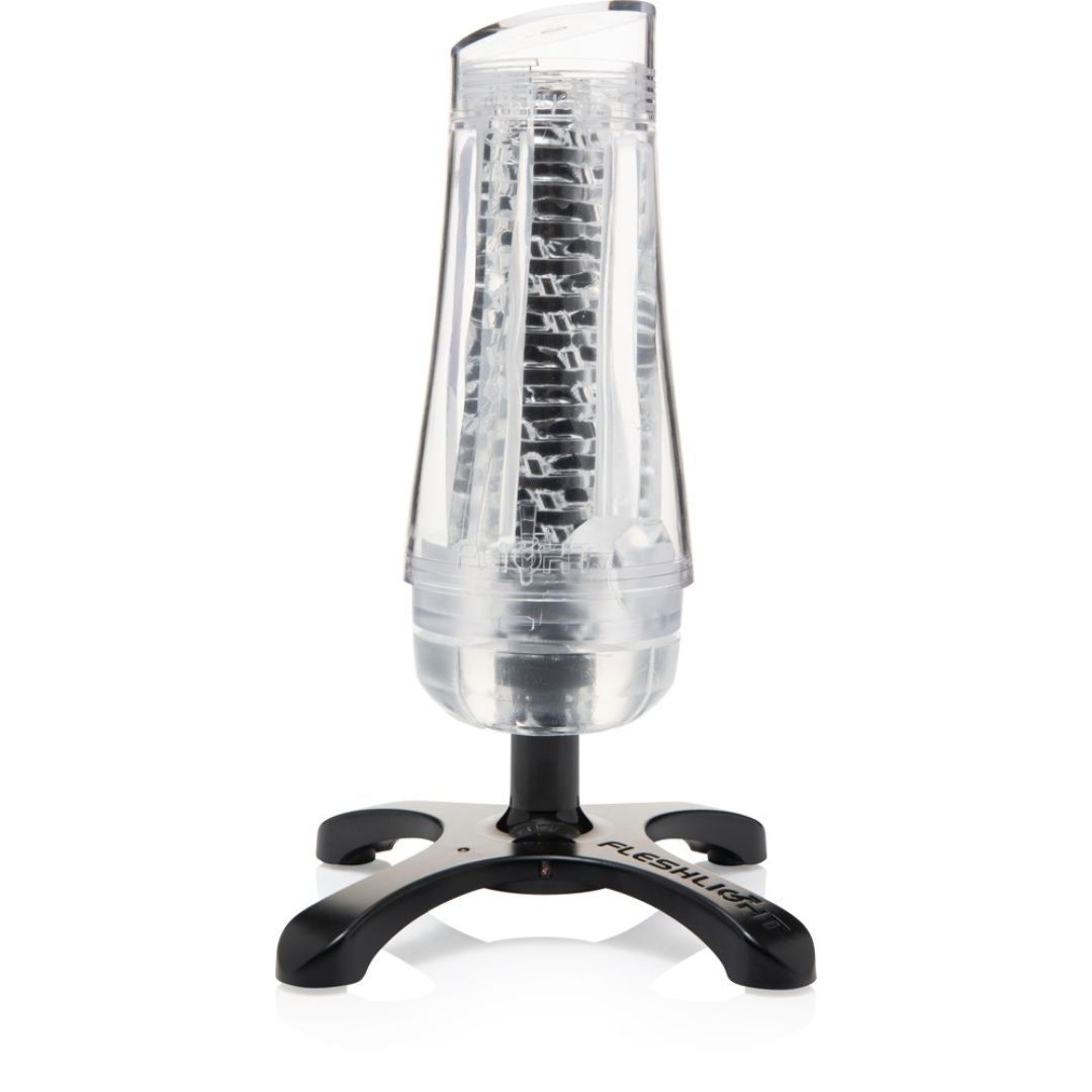 Cylindre transparent avec intérieur noir, sur un socle noir. Le socle porte l'inscription FLESHLIGHT.