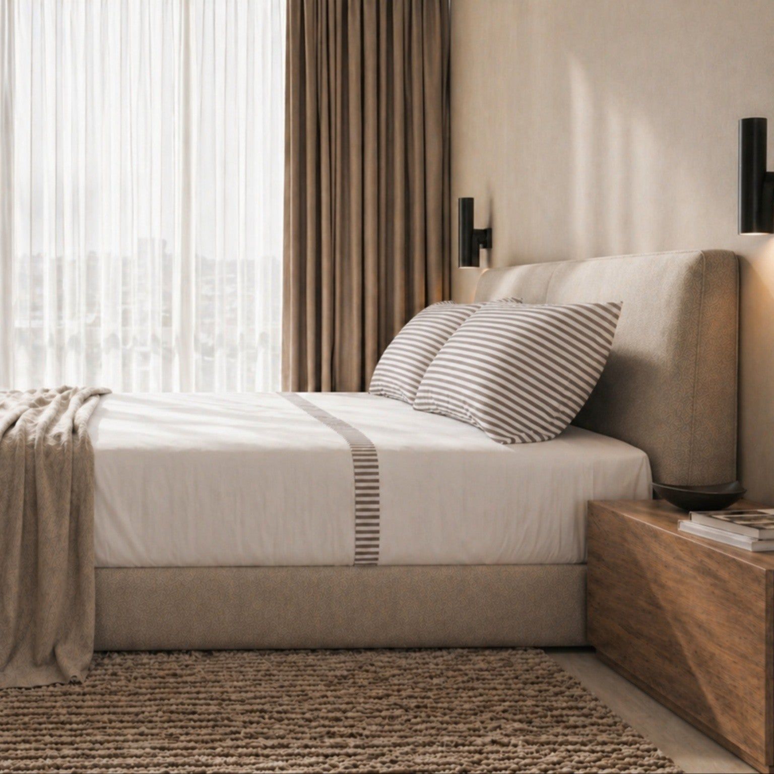Een opgemaakt bed met gestreept beddengoed en een deken.